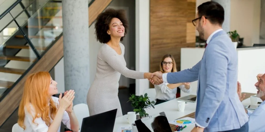 Advisor and client shaking hands in a modern office after a successful investment agreement