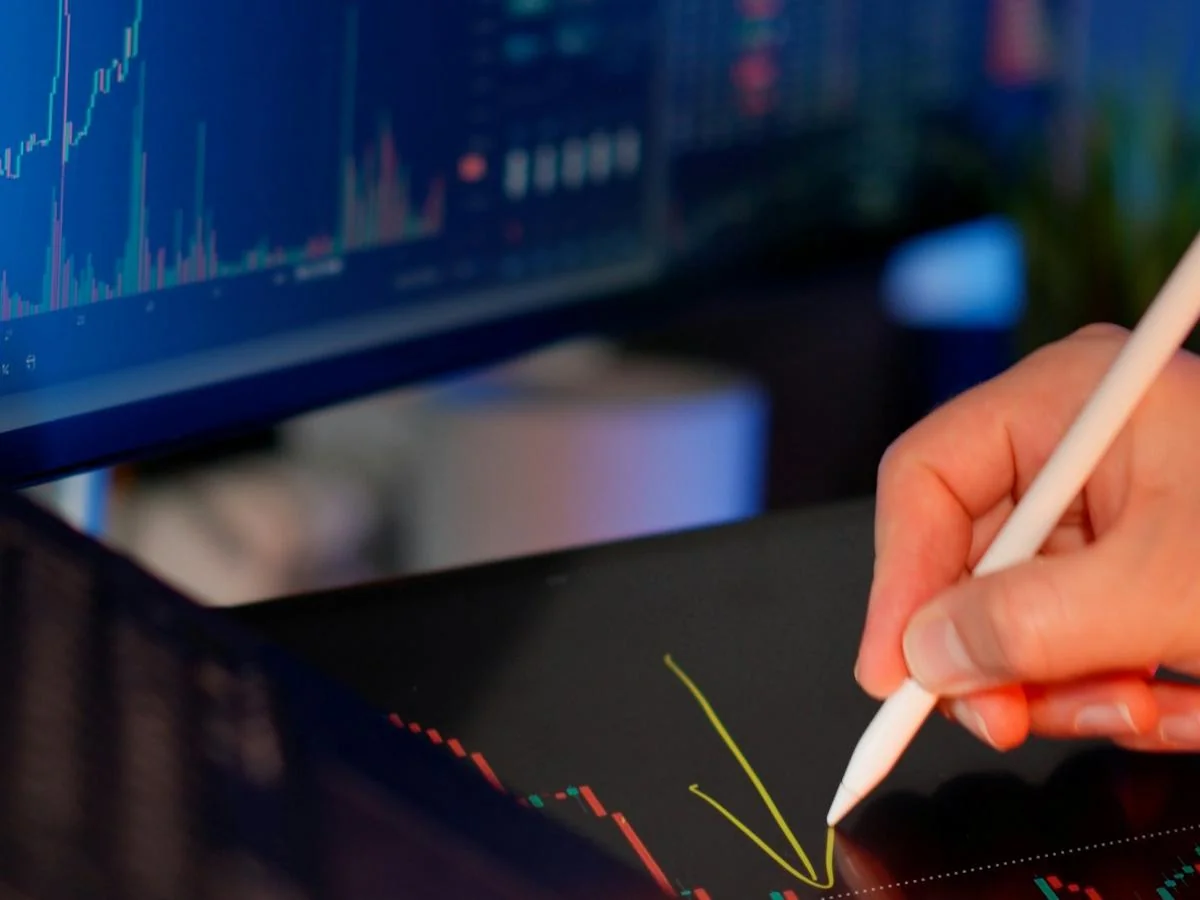 Hand using a digital stylus to annotate financial charts
